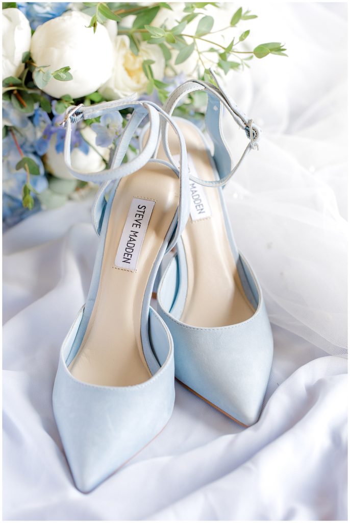 Pale blue Steve Madden suede shoes setting in front of blue hydrangeas and white flowers at a Georgetown Kentucky wedding.