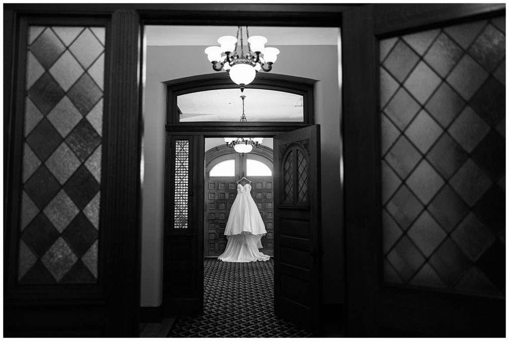 A large white stress hanging from a door. Camera is placed several rooms back looking through two door to see the dress at a Georgetown Kentucky wedding.